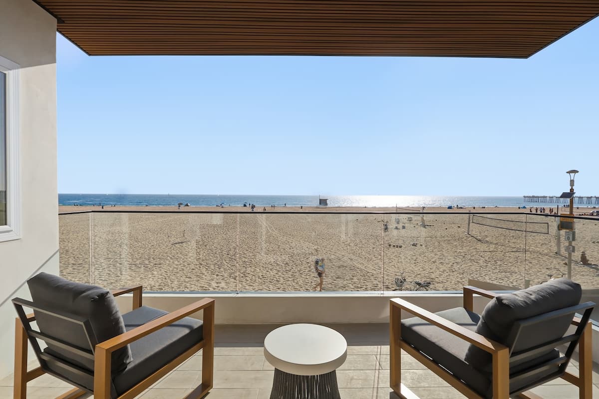 Covered oceanfront balcony with lounge chairs above the volleyball courts