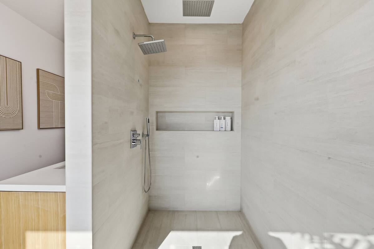 Large glass shower with warm stone tile